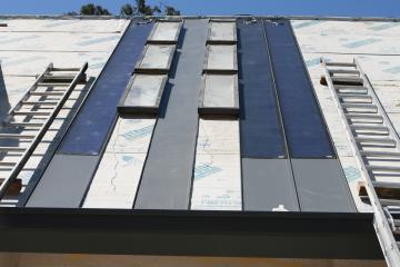 [First few standing seam metal roof panels in place]